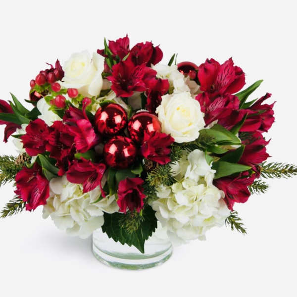 Red and white floral arrangement in a clear glass vase with red ornaments