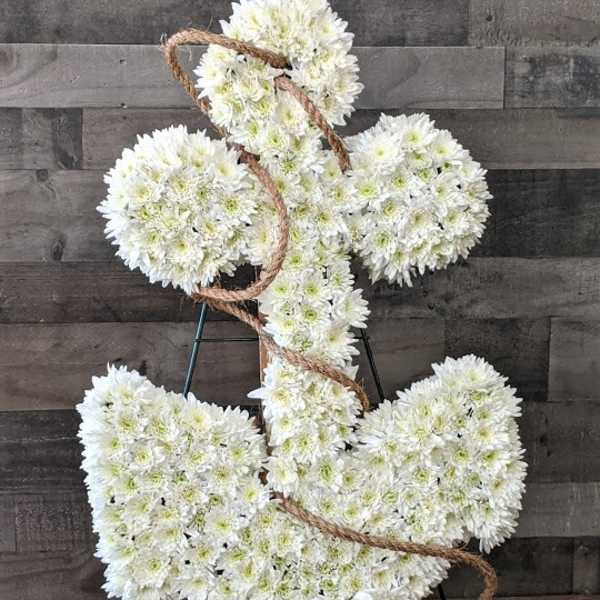 White floral anchor-shaped sympathy arrangement with rope on a stand