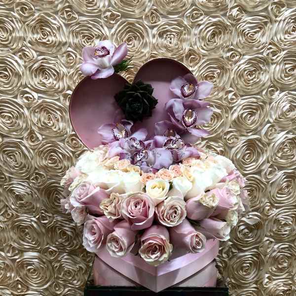 Heart-shaped box with pink roses and orchids on a rose-patterned backdrop