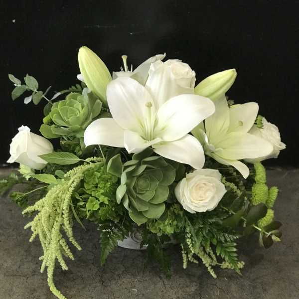 White lilies and roses in a low green-and-white arrangement