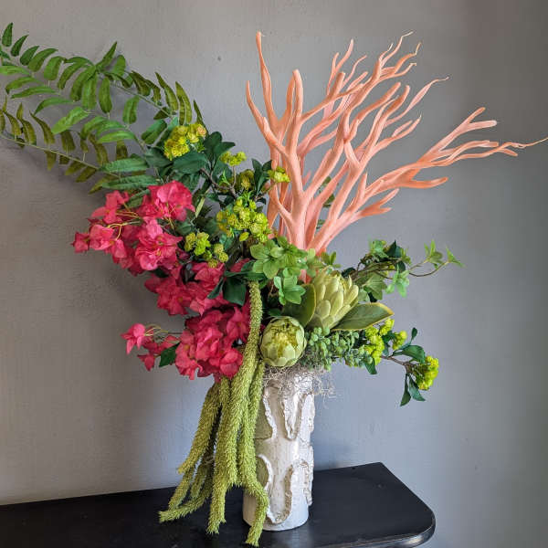 Pink and green floral arrangement in a white vase with coral branches