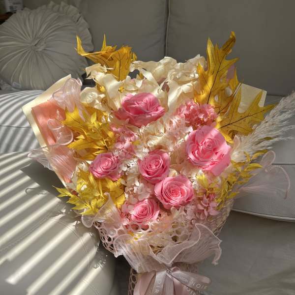 Bouquet of pink roses with pale filler flowers and gold leaves
