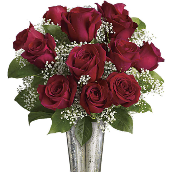 Red roses arranged in a clear glass vase with baby's breath