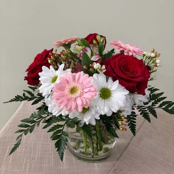 Bouquet of red roses and pink gerbera daisies in a clear glass vase