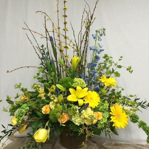 Tall mixed flower arrangement with yellow lilies and gerbera daisies in a vase