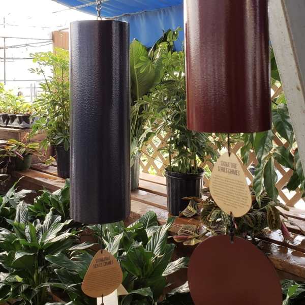 Hanging metal wind chimes above potted houseplants