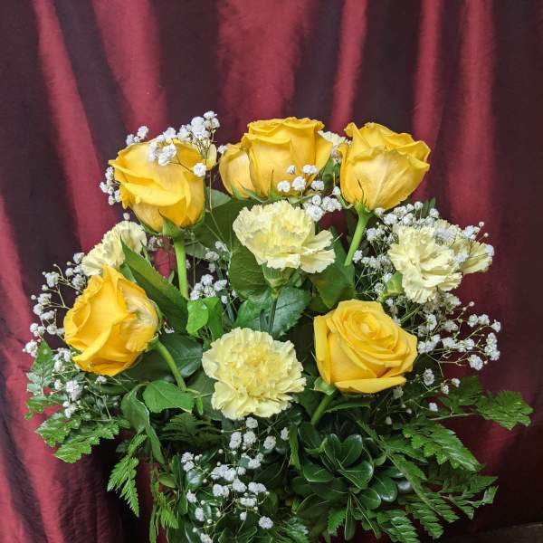 Yellow roses and pale carnations in a glass vase