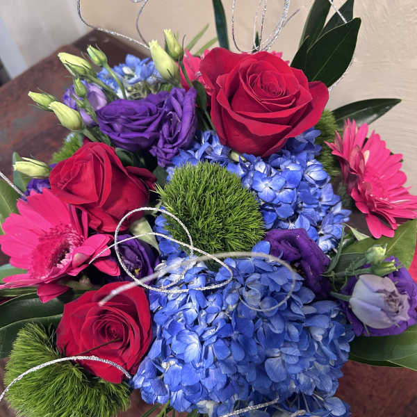 Bouquet of red roses, blue hydrangeas, and pink gerbera daisies