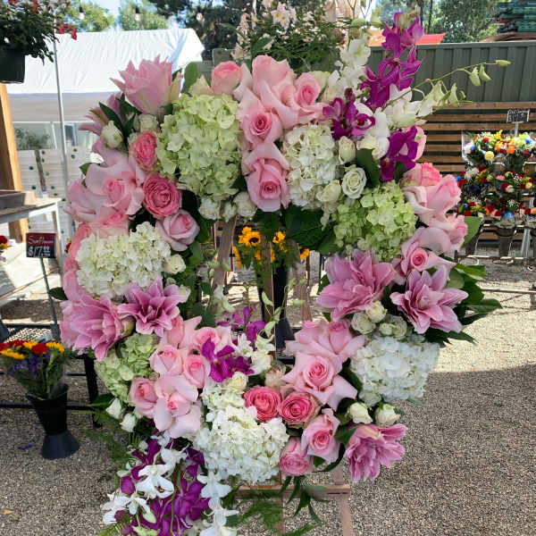 Large floral wreath of pink roses, hydrangeas, lilies, and orchids on an easel