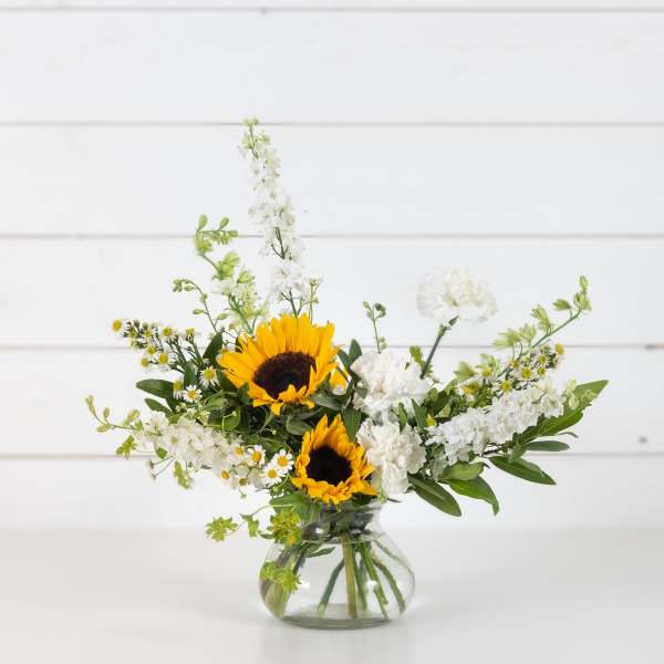 Sunflowers and white flowers in a clear glass vase