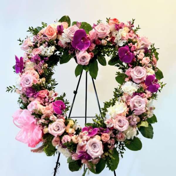 Large floral wreath of pink and purple blooms on a black stand
