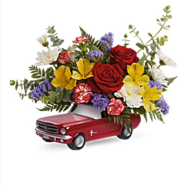 Flower arrangement in a red toy car with roses and mixed blooms