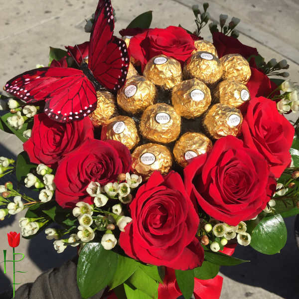 Red roses arranged around Ferrero Rocher chocolates with a red butterfly topper