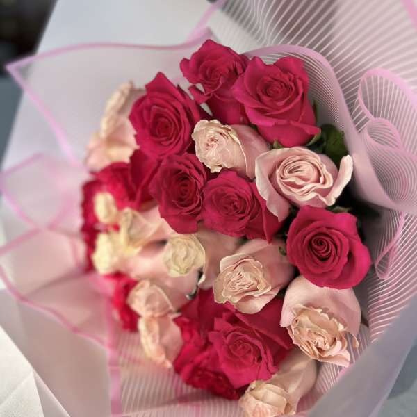 Bouquet of hot pink and blush roses wrapped in pink paper