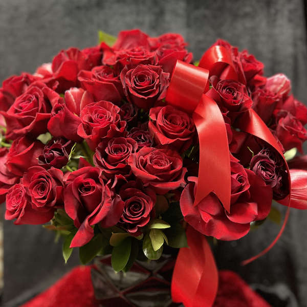 Bouquet of red roses with a red ribbon in a dark vase