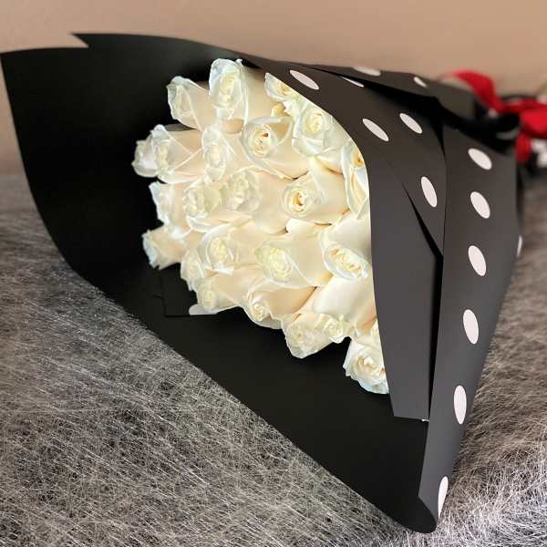 Bouquet of white roses wrapped in black paper with white polka dots