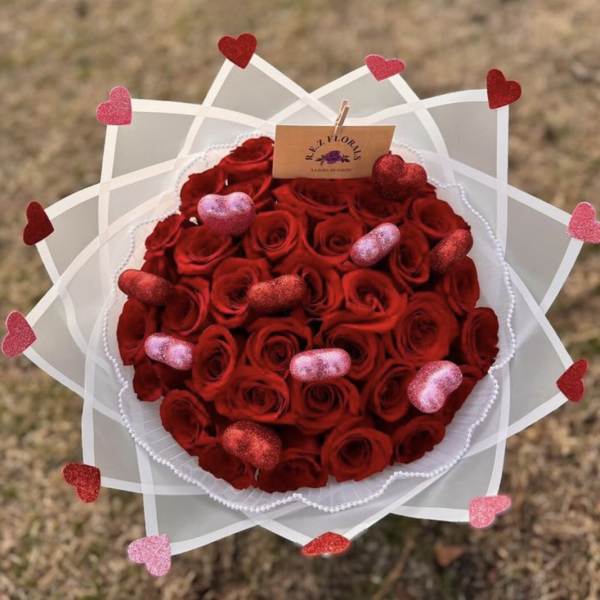 Round bouquet of red roses with heart decorations and white wrap