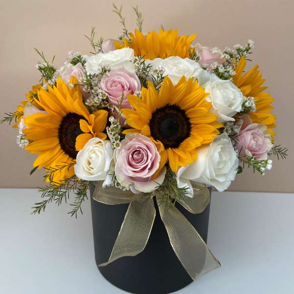 Bouquet of sunflowers and pink and white roses in a black box