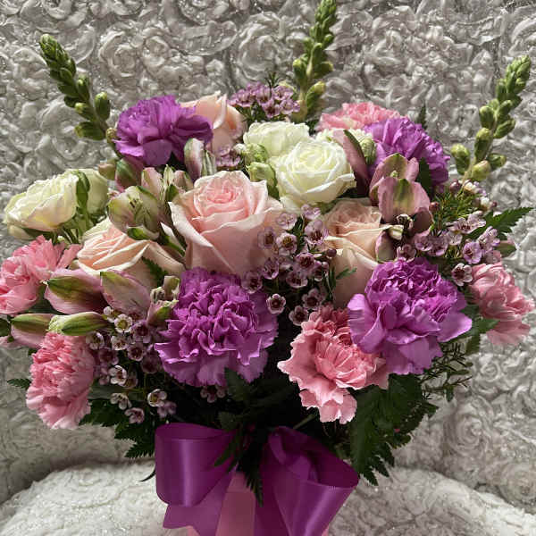 Pink and white rose bouquet with carnations in a pink box tied with a purple ribbon
