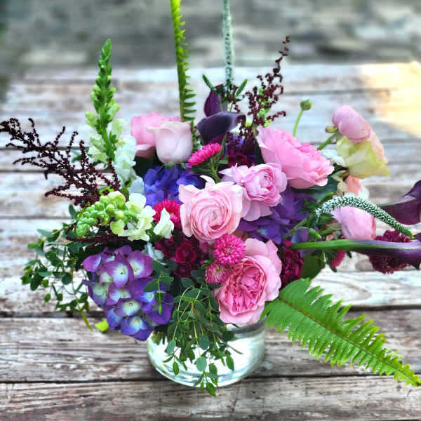 Mixed bouquet of pink, purple, and white flowers in a glass vase