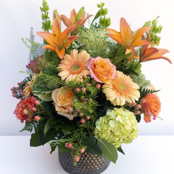 Orange lilies and peach roses in a dark textured vase