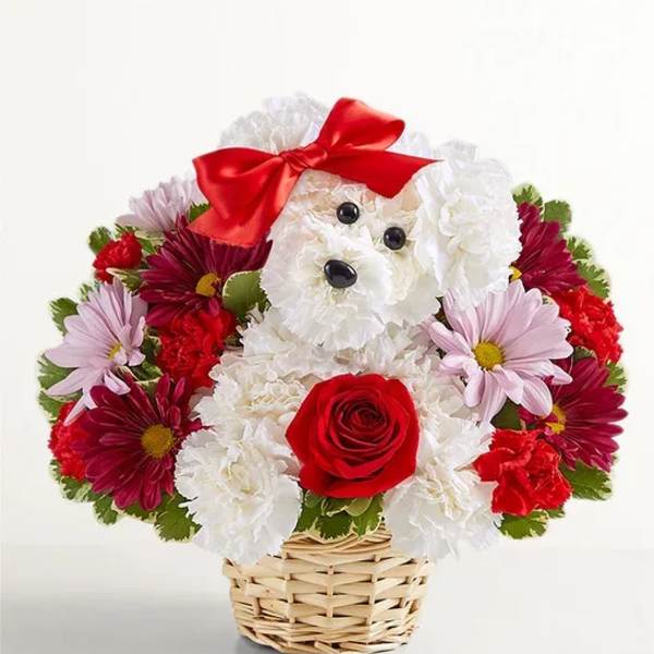 Flower arrangement shaped like a white dog with a red bow in a wicker basket