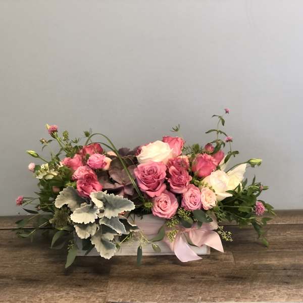 Pink and white rose arrangement in a low rectangular box with a ribbon