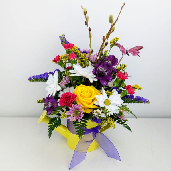 Mixed bouquet in a yellow watering can with a purple ribbon
