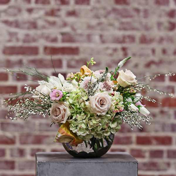 Mixed bouquet of pale roses and white blooms in a round vase