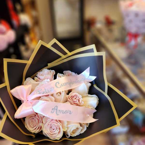 Pink and white rose bouquet wrapped in black paper with a pink ribbon