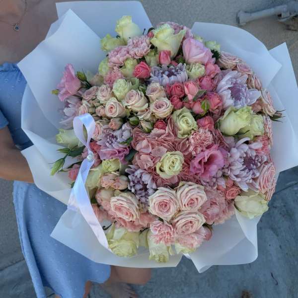 Large pastel bouquet of roses, carnations, and chrysanthemums wrapped in white paper