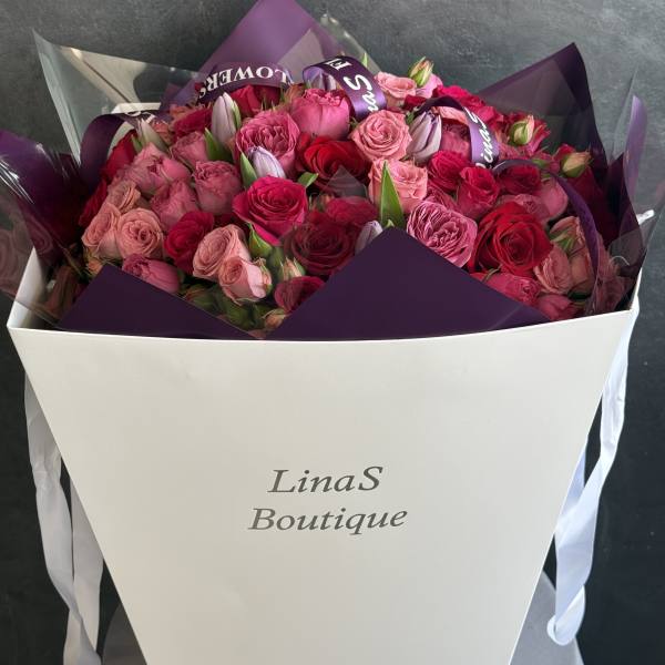 Bouquet of pink and red roses wrapped in purple paper
