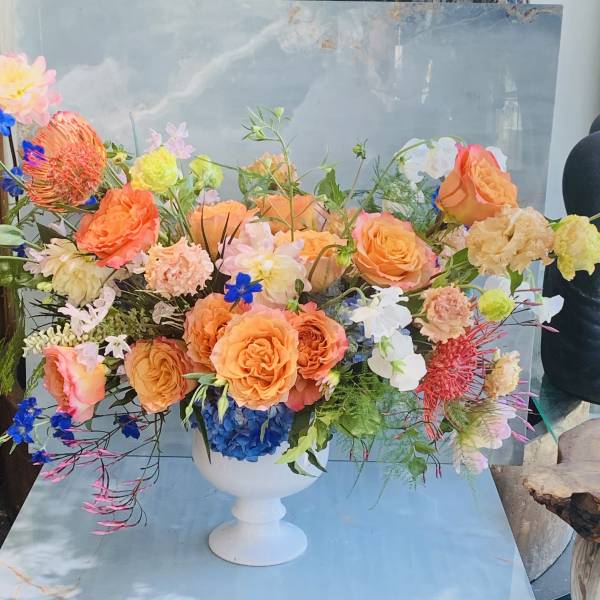 Large mixed floral arrangement in a white pedestal vase