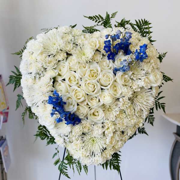 Heart-shaped white floral standing arrangement with blue accents