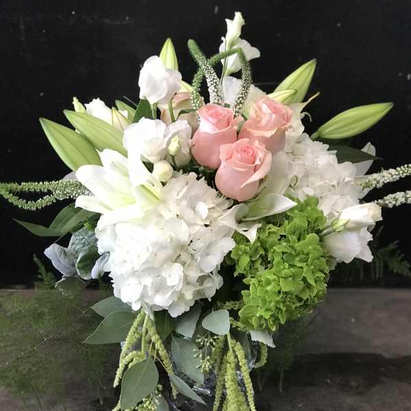 Bouquet of pink roses, white lilies, and white hydrangeas with trailing greenery