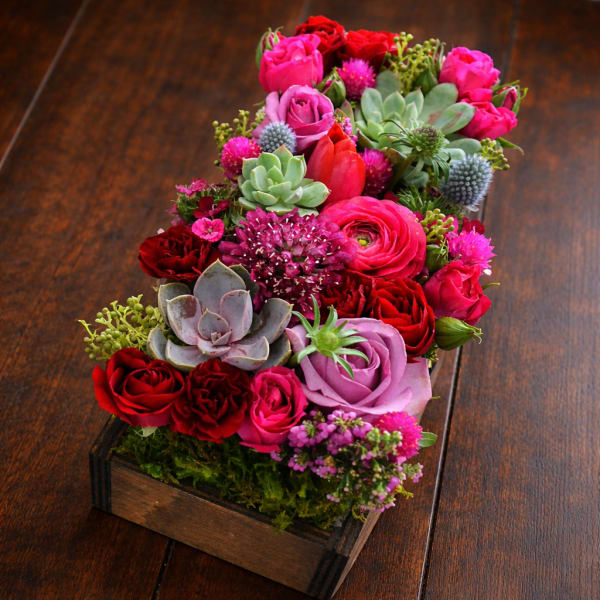 Mixed pink and red roses with succulents in a wooden box