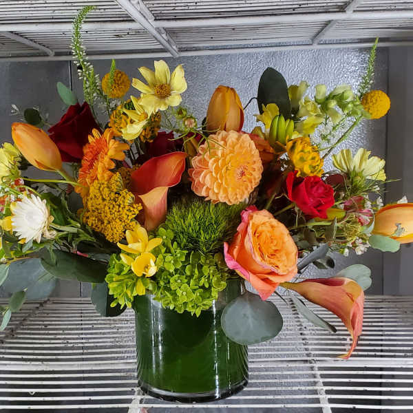 Mixed bouquet in a glass vase with orange, yellow, red, and white flowers
