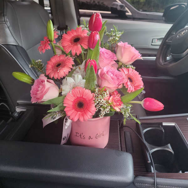 Pink 'It's a Girl' flower arrangement with tulips, gerbera daisies, and roses in a small container