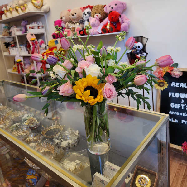 Mixed bouquet of pink roses and tulips with a sunflower in a glass vase