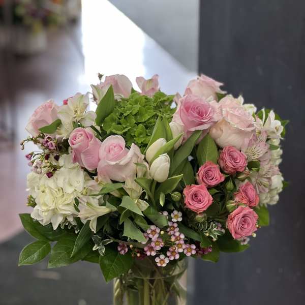 Pink roses and white flowers arranged in a clear glass vase