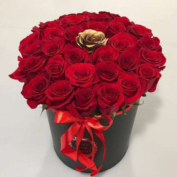 Red roses arranged in a black hatbox with a red ribbon