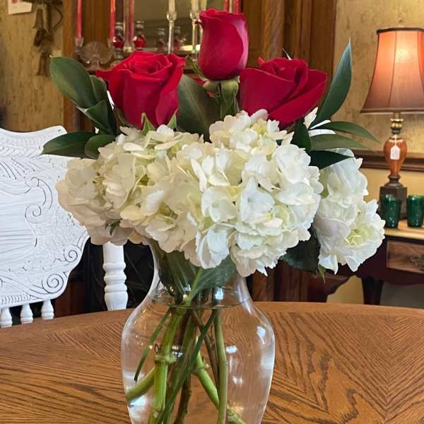 Red roses and white hydrangeas in a clear glass vase