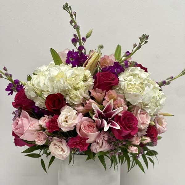Pink and white floral arrangement in a white hat box