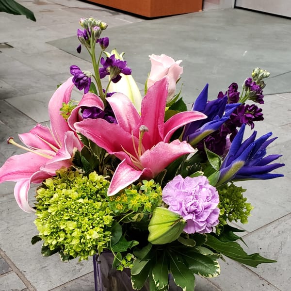 Pink and purple lilies arranged in a purple glass vase