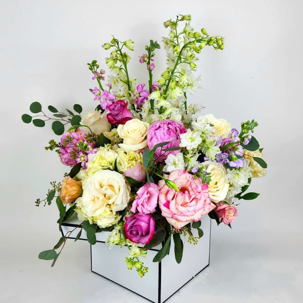Mixed pink, cream, and white flowers arranged in a white box