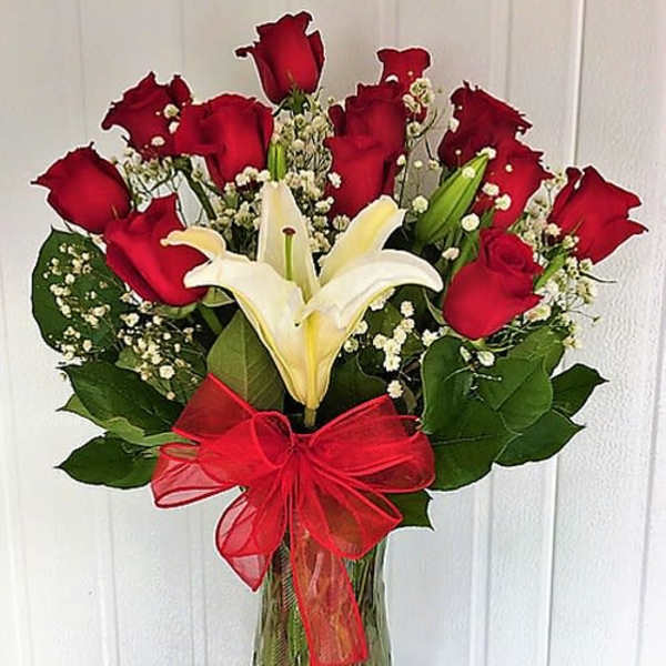 Bouquet of red roses and white lilies in a glass vase with a red bow