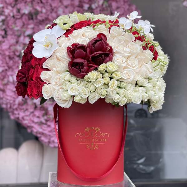 Large red and white rose arrangement in a red hat box with white orchids