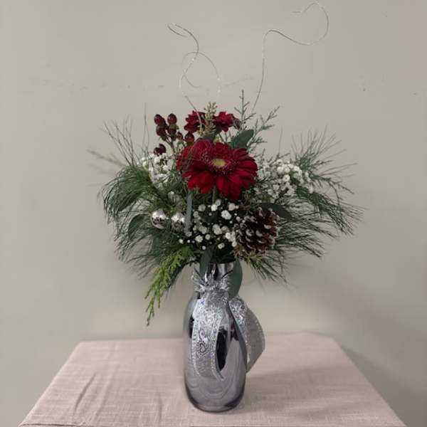 Red gerbera bouquet in a silver vase with pinecones and ribbon