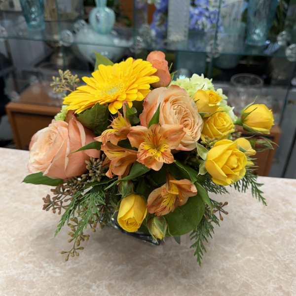 Bouquet of yellow and peach flowers in a low vase