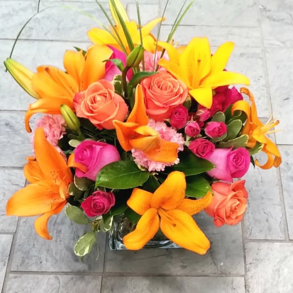 Bright bouquet of orange lilies and pink roses in a glass vase